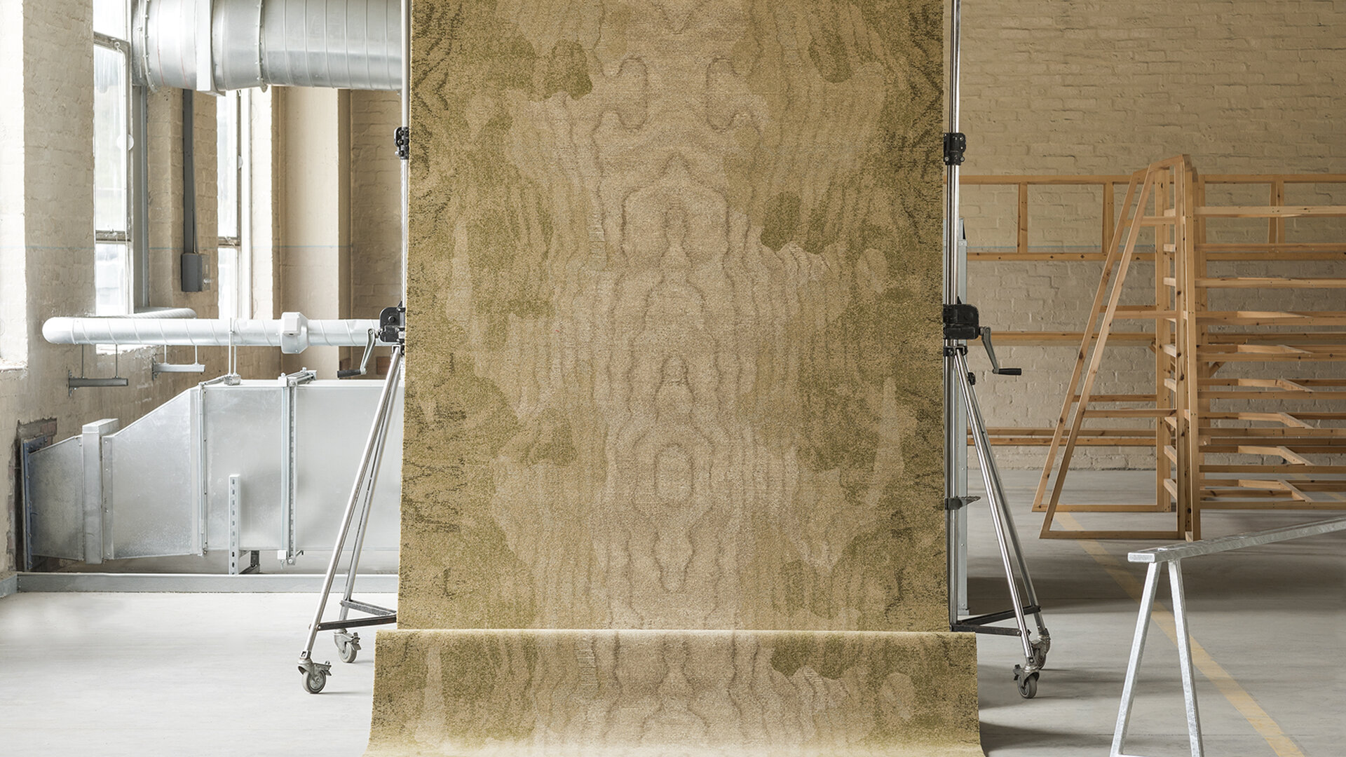 A carpet with a wood like print rolling over a metal bar and onto another metal bar.