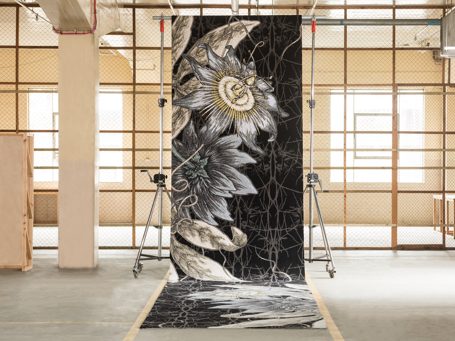 Large patterned carpet in a room in front of a wood and wire wall.