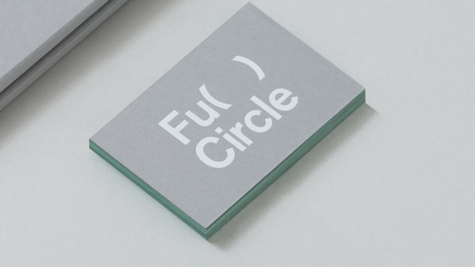 A grey business card that has white type on it. The type reads "Full Circle"