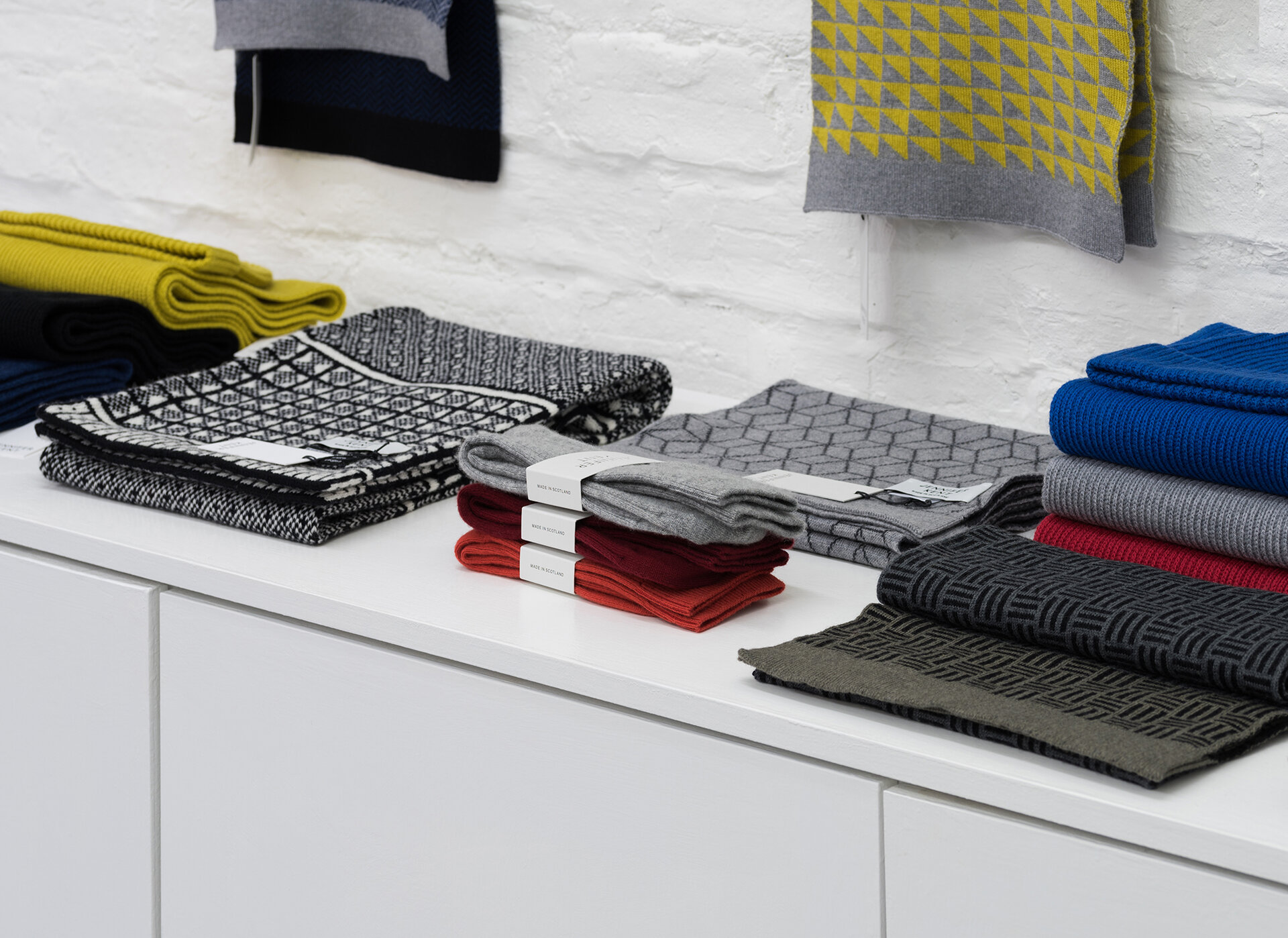 Scarfs and socks sitting on a unit in a shop.