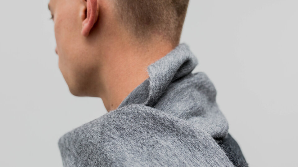 Detail of a man wearing a grey scarf around his neck.