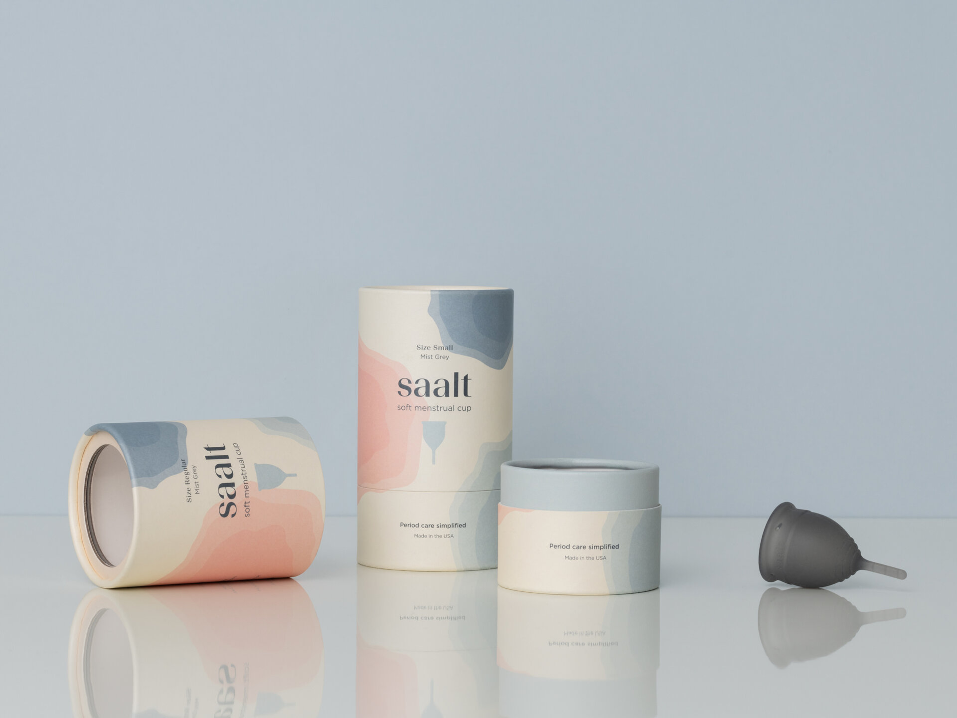 Two saalt packaging tubes. One tube is open and a saalt cup sits beside it.