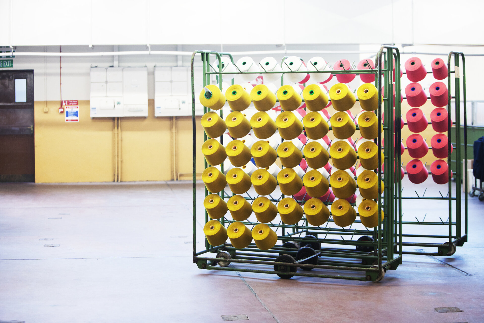 A trolly full of yellow looms with a trolly of red looms in the background.